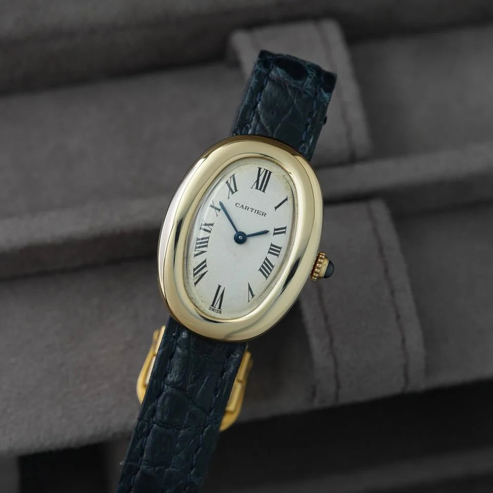 Montre ovale à cadran blanc et bracelet noir portée au poignet